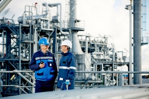 Two engineers in front of a refinery